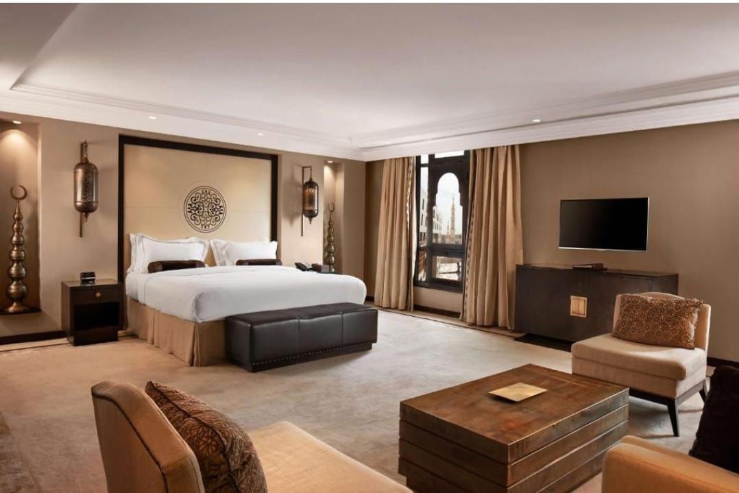 Luxurious hotel room with king-sized bed, elegant decor, and large window with curtains.
