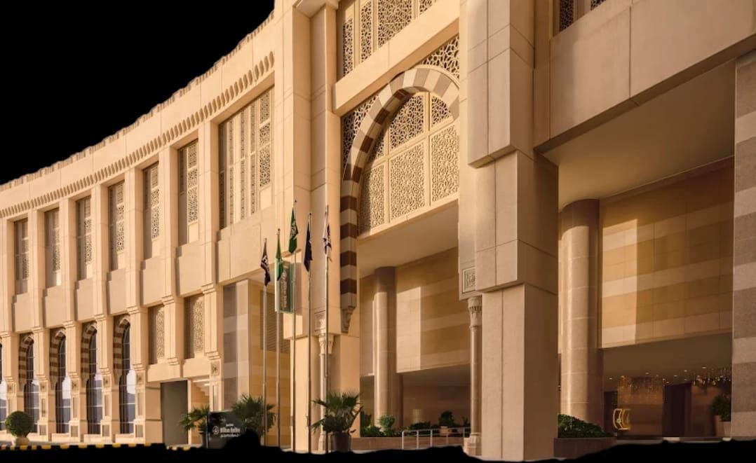 Elegant facade of a large building with arches, intricate designs, and multiple flags.