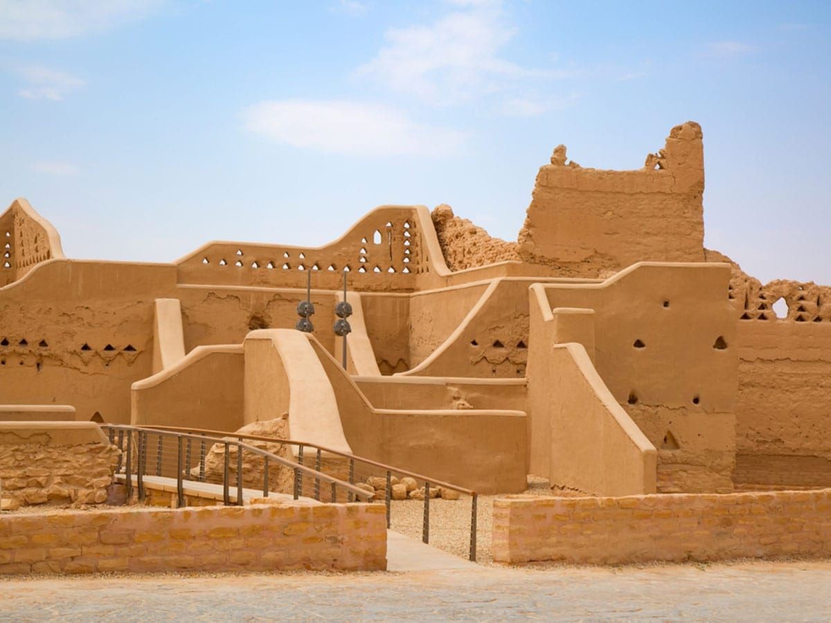 Ancient mudbrick ruins with intricate geometric patterns and a ramp, under a clear blue sky.
